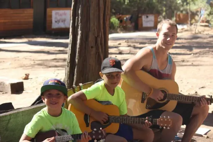 Campers and counselor playing guitar